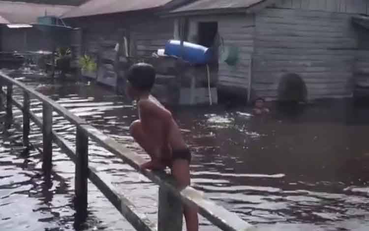 Sejumlah anak-anak saat berenang di tengah banjir yang melanda.
