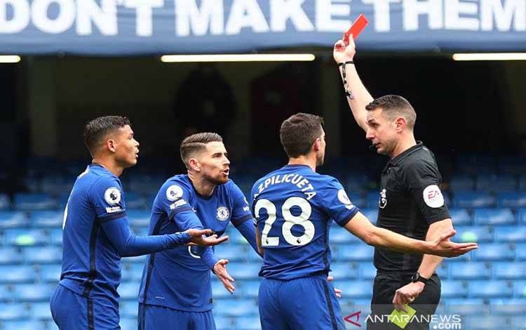 Wasit David Coote (kanan) memperlihatkan kartu merah kepada bek Chelsea Thiago Silva (kiri) dalam lanjutan Liga Inggris melawan West Bromwich Albion di Stadion Stamford Bridge, London, Inggris, Sabtu (3/4/2021)