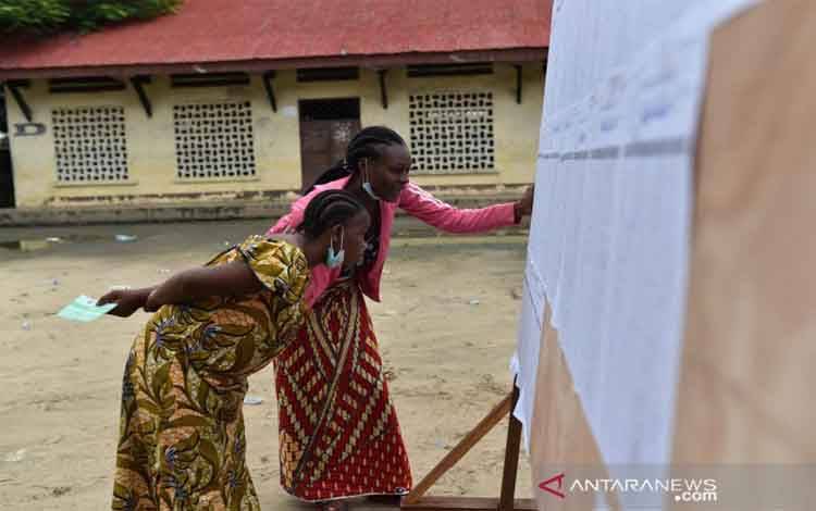 Para perempuan mencari nama mereka di daftar pemilih di sebuah tempat pemungutan suara saat pemilihan presiden di Brazzaville, Republik Kongo, Minggu (21/3/2021)