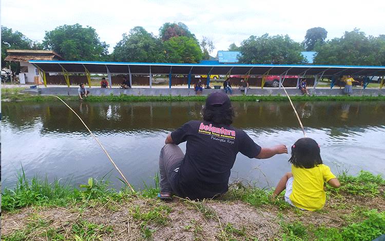 Pengunjung kolam pemancingan, seorang bapak dan putrinya memancing ikan bersama di Kolam Pemancingan Lewu Panatau, Minggu, 23 Mei 2021.