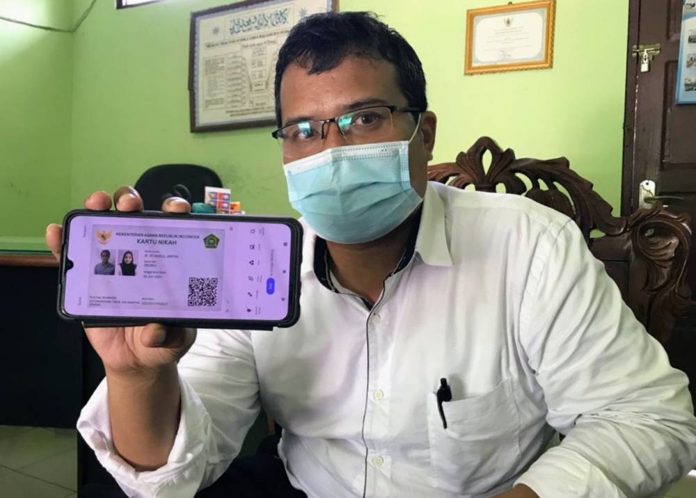 Kepala KUA Baamang, Ahmad Mulyadi menunjukkan kartu nikah digital