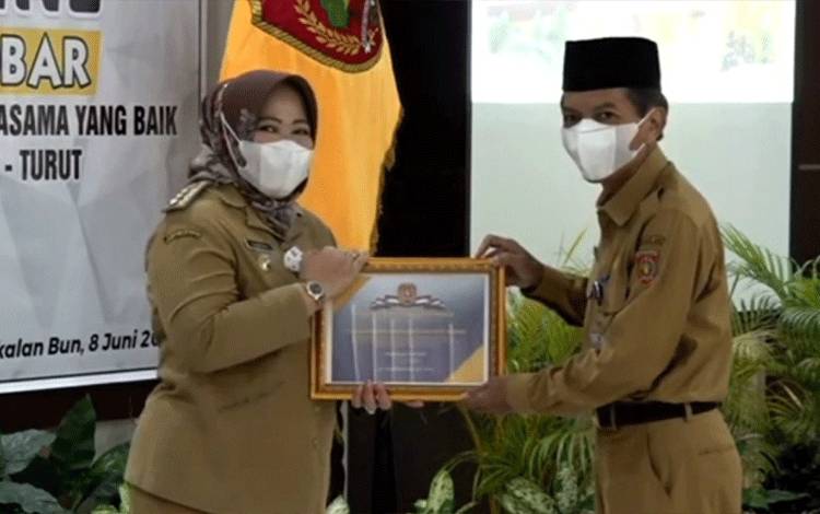 Bupati Kobar Nurhidayah saat menyerahkan piagam penghargaan kepada Kepala BPKAD Kobar Rochim Hidayat.