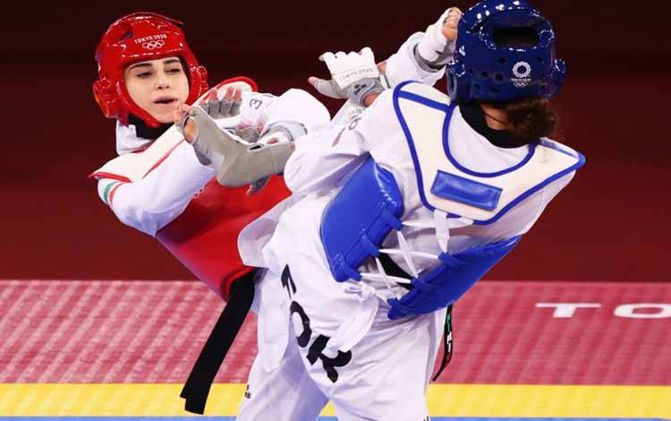 Atlet taekwondo dari Tim Olimpiade Pengungsi Kimia Alizadeh asal Iran (kiri) bertarung melawan Nahid Kiyanichandeh yang juga dari Iran (kanan) pada nomor pertandingan kualifikasi putri kelas 57kg di Makuhari Messe Hall A, Chiba, Jepang, Minggu (25/7/2021)