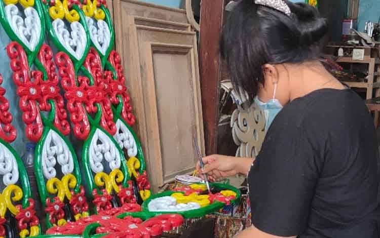 Pengerajin sedang mengecet ornamen khas Dayak
