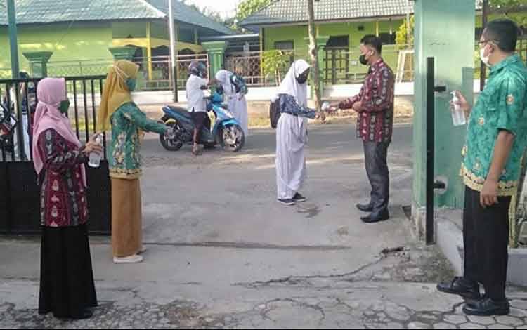Peserta didik MTsN 1 Kapuas sebelum mengikuti PTMT dicek suhu tubuh.