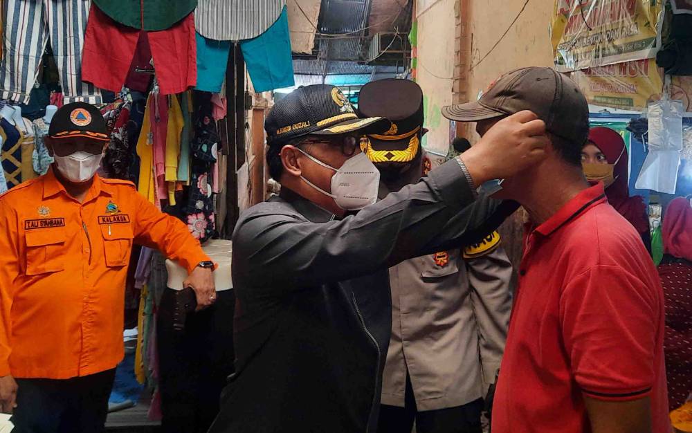 Ketua DPRD Kobar Rusdi Gozali memasangkan masker kepada pengunjung pasar dalam kegiatan Oeperasi Yustisi pendisiplinan Prokes.