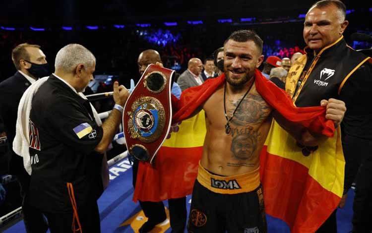 Petinju Vasiliy Lomachenko tersenyum bahagia sambil memegang sabuk juara usai mengalahkan Richard Commey dalam pertandingan perebutan gelar juara kelas ringan WBO Intercontinental di Madison Square Garden, New York, AS, Sabtu (11/12/2021)