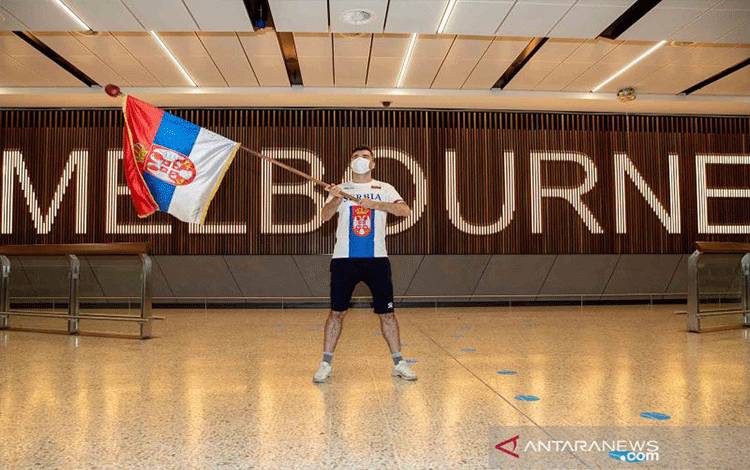 Seorang penggemar mengibarkan bendera nasional Serbia saat menunggu kedatangan petenis Novak Djokovic di Bandara Internasional Melbourne, Melbourne, Australia, Kamis (6/1/2022). Pemerintah Australia akhirnya membatalkan visa masuk petenis nomor satu dunia Novak Djokovic yang sebelumnya mendapat dispensasi dari kewajiban vaksin COVID-19 sebelum memasuki negara Kangguru tersebut. ANTARA FOTO/AAP Image/Con Chronis/via REUTERS/wsj.