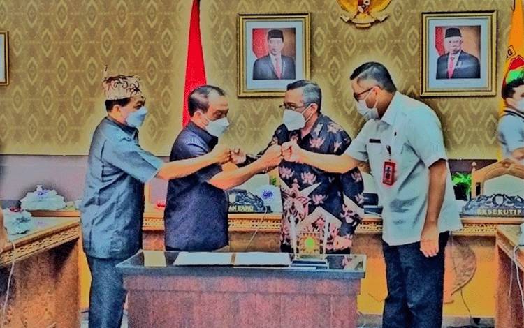 Ketua Pansus pembahasan Perda RUED, Hendri bersama Wakil I DPRD Kalteng, Abdul Razak bersalaman dengan pihak DEN seusai penandatanganan persetujuan naskah Perda RUED.