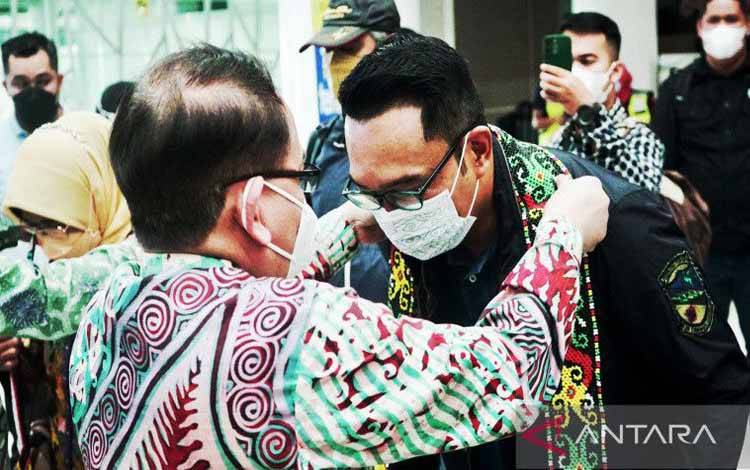 Kepala Disperindagkop dan UKM Kaltim HM Yadi Robyan Noor mengalungkan manik selamat datang menyambut kedatangan Kang Emil