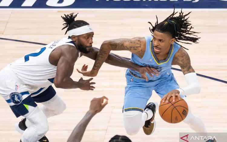 Pebasket Memphis Grizzlies Ja Morant (kanan) mendribel bola dan berupaya melewati penjagaan pebasket Minnesota Timberwolves Patrick Beverley (22) dalam laga play off NBA, di Target Center, Minneapolis, Minnesota, Amerika Serikat, Sabtu (23/4/2022)