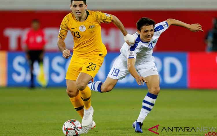 Pesepakbola Australia Tom Rogic (kiri) dan Otabek Shukurov dari Uzbekistan berebut bola dalam babak 16 besar Piala AFC di Stadion Khalifa bin Zayed, Al Ain, UEA, Senin (21/9/2021)