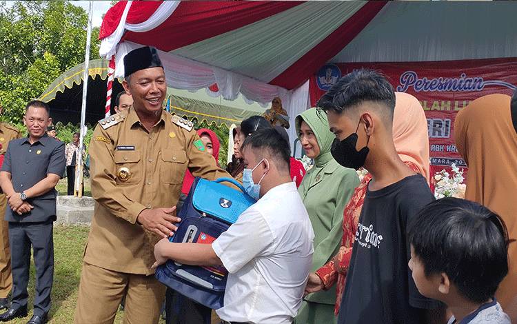 Bupati Sukamara, Windu Subagio saat menyerahkan tas kepada anak berkebutuhan khusus.