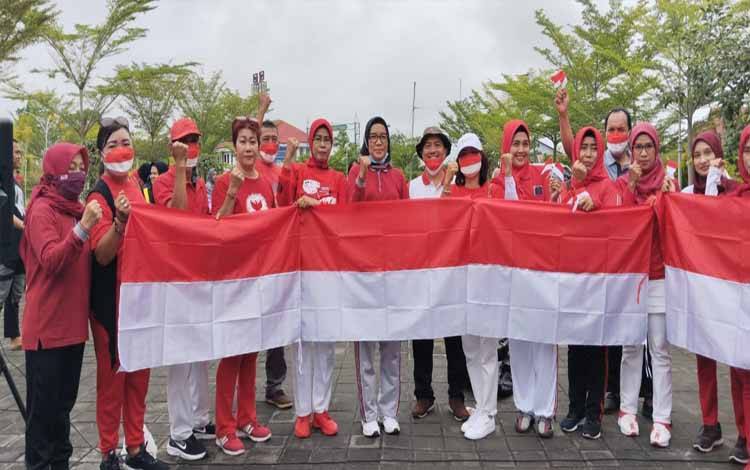 Sekretaris Daerah Kota Palangka Raya, Hera Nugrahayu, menyerahkan dan membagikan secara simbolis bendera kepada warga di area Taman Nyahu Papan Taliwu. (Foto: HENDRI)