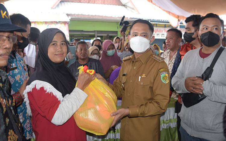 Wali Kota Palangka Raya, Fairid Naparin menyerahkan paket sembako kepada warga di Kelurahan Palangka saat operasi pasar. (FOTO: WULAN/DISKOMINFO PALANGKA RAYA)