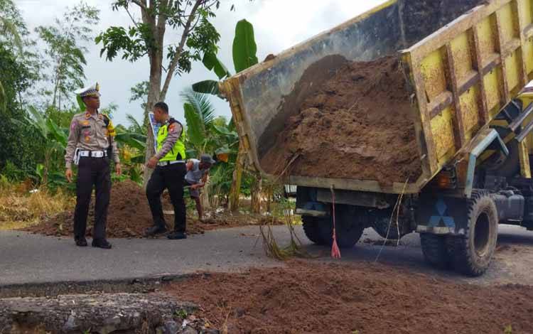 Personel Satuan Lalu Lintas Polres Seruyan di bantu warga sekitar melakukan pengurukan badan jalan Budi Utomo Kuala Pembuang, tidak jauh dari SMAN 1 Kuala Pembuang (Foto : Satlantas Polres Seruyan)