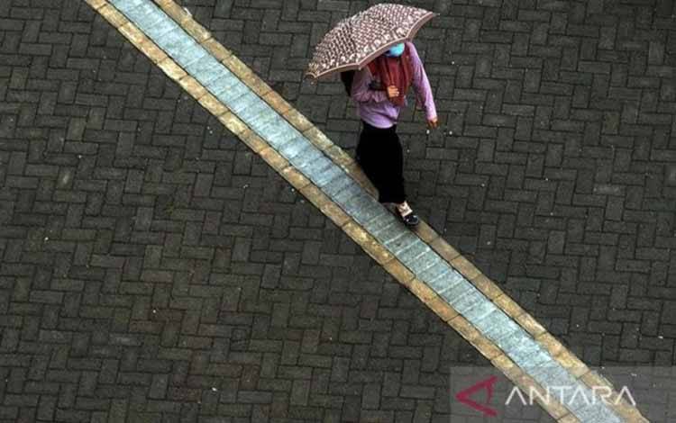Arsip Foto - Seorang warga berjalan menggunakan payung saat hujan turun di Kota Makassar, Sulawesi Selatan. (ANTARA FOTO/ABRIAWAN ABHE)