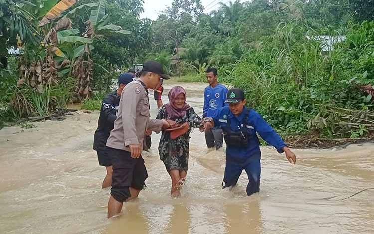 Relawan dan anggota Bhabinkamtibmas Polres Barito Timur membantu menyeberangkan warga di lokasi banjir Desa Pangkan, Selasa, 28 Maret 2023. (FOTO: BPK SAMUJA)