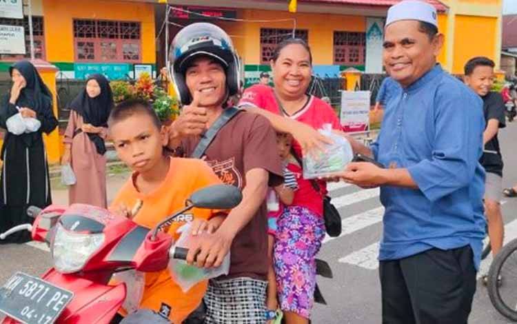 Kepala SD Negeri 1 Kuala Pembuang I, Kirsam saat membagikan takjil kepada warga yang melintas di depan SD Negeri 1 Kuala Pembuang I. (FOTO: IST)