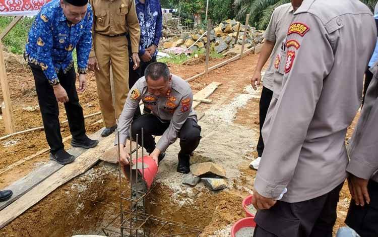 Kapolres Lamandau AKBP Bronto Budiyono saat melakukan peletakan batu pertama menandai dimulainya pembangunan Kantor Posyan Menthobi Raya. (FOTO : HENDI NURFALAH)