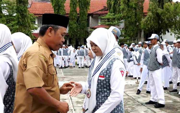 Kepala SMAN 1 Muara Teweh, Razikinnor resmi melepas siswa dan siswi kelas XII ditandai dengan mengalungkan medali generasi ke 63 di halaman SMAN 1 Muara Teweh, Senin, 8 Mei 2023. (FOTO: DHANI)