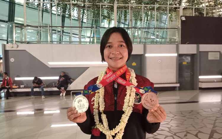 Ester Nurumi Tri Wardoyo memamerkan medali SEA Games saat berada di terminal tiga bandara Soekarno-Hatta, Tangerang, Jumat. ANTARA/Fajar Satriyo)