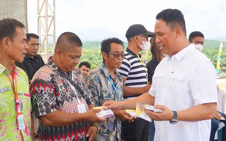 Bupati Hendra Lesmana membagikan buku rekening dimana hasil dari kebun plasma ditransfer kepada para penerima hak. (FOTO: HENDI NURFALAH)