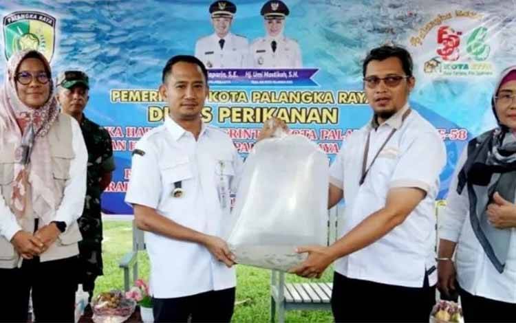 Wali Kota Palangka Raya, Fairid Naparin memimpin Restoking 50 ribu benih ikan di Danau Rigei. (FOTO: DISKAN)