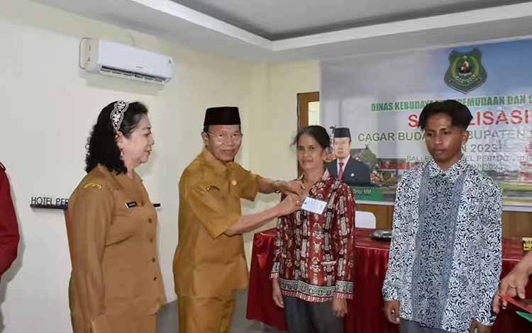 Plt Bupati Kapuas saat menyematkan tanda peserta sosialisasi cagar budaya yang digelar Disbudpora Kapuas. (FOTO: IST)