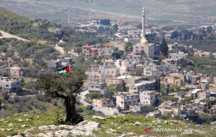 Bendera Palestina digantung di pohon selama protes terhadap pemukiman Yahudi di desa An-Naqura dekat Nablus, di West Bank yang diduduki Israel, Senin (29/3/2021). REUTERS/Raneen Sawafta/AWW/sa. (REUTERS/RANEEN SAWAFTA)