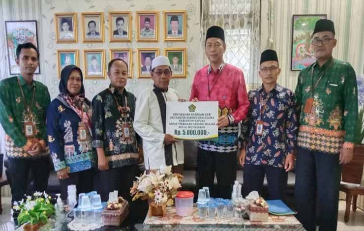 Kepala Kemenag Kapuas, Hamidhan menyerahkan bantuan dari UPZ Kemenag kepada MTs Al Mustajabah, Rabu 12 Juli 2023. (FOTO: IST)