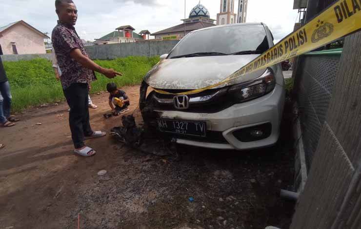 Pemilik mobil terbakar Fitriadi saat menunjukkan mobilnya di garis polisi (Foto : Pathur)