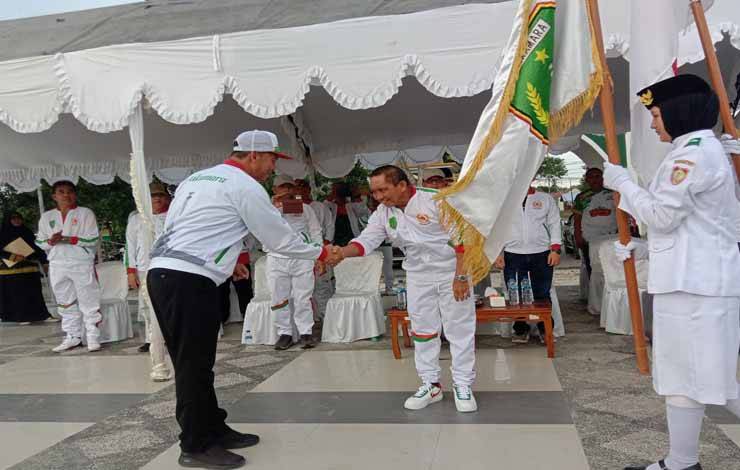 Bupati Sukamara, Windu Subagio menyerahkan bendera kepada Ketua KONI Sukamara, Muhammad Yamin pada pelepasan Kontingen Porprov XII, Jumat, 21 Juli 2023. (FOTO:NORHASANAH)