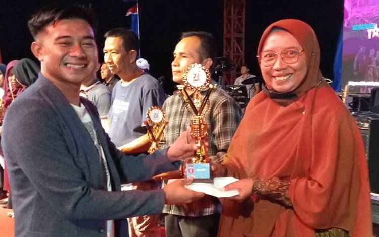 Ketua DPD KNPI Seruyan Zulkipli Khaidir menyerahkan piagam dan tropi kepada Kepala SDN 3 Kuala Pembuang I Asri Sutarsih (Foto : Ist)
