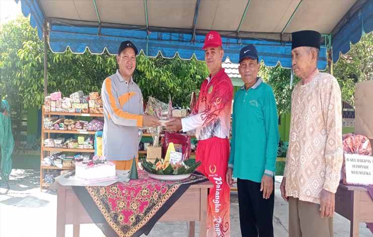Kepala MIN 5 Kota Palangka Raya, Muhamad Asran Dirun memberi potongan tumpeng pertama kepada Lurah Banturung, Bambang pada Sabtu, 25 November 2023.(FOTO: TESTI PRISCILLA)