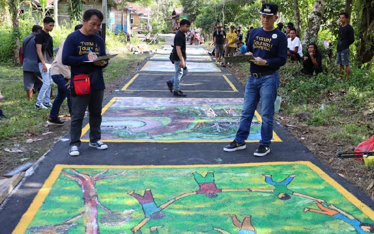 Bupati Gunung Mas Jaya S Monong (kanan)saat menilai hasil karya pada lomba mural jalan, Sabtu, 9 Desember 2023. (FOTO: DISKOMINFOSANTIK GUMAS)