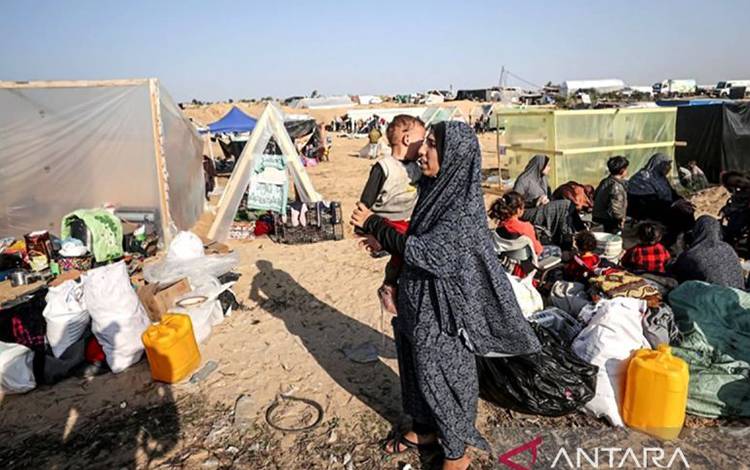 Arsip - Seorang perempuan menggendong anak di pengungsian di Gaza. (ANTARA/Anadolu/aa)