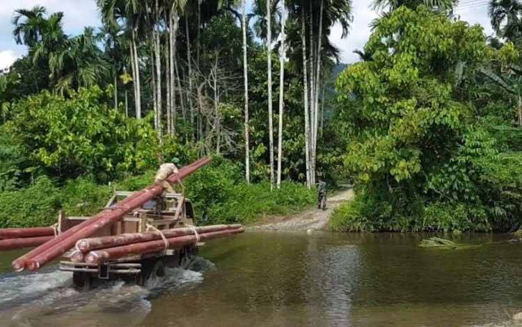 Petugas PLN membawa material pendukung kelistrikan menembus sungai ke Desa Gunung Menasaha, Kecamatan Setia Bakti, Kabupaten Aceh Jaya, Provinsi Aceh yang jaraknya kurang lebih 200 kilometer dari Banda Aceh. ANTARA/HO-PLN