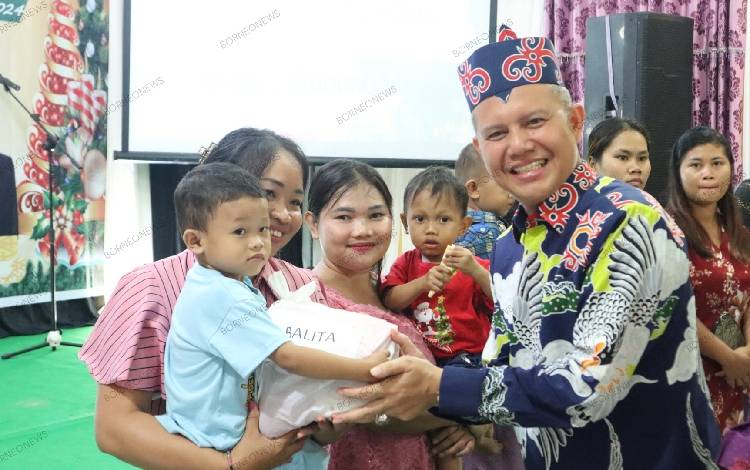 Bupati Gunung Mas Jaya S Monong saat menyerahkan bantuan makanan tambahan kepada balita untuk cegah stunting. (FOTO: DISKOMINFOSANTIK