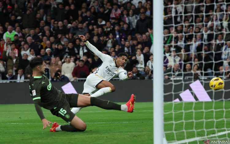 Gelandang Real Madrid Jude Bellingham (kanan) menendang bola untuk menjadi gol kedua timnya pada pertandingan Liga Spanyol melawan Girona di Stadion Santiago Bernabeu, Madrid, Sabtu (10/2/2024). (ANTARA/AFP/PIERRE-PHILIPPE MARCOU)