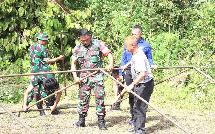 Warga bersama Satgas TMMD ke 119 saat membersihkan serta memasang tenda. (FOTO: DHANI)