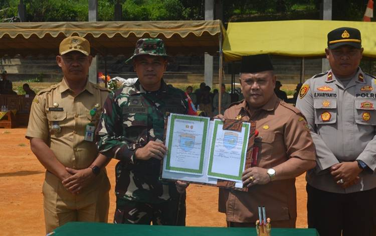 Dandim Pangkalan Bun Letkol Arm Yoga Permana dan Plh Sekda Kobar Juni Gultom menunjukan naskah serah terima pekerjaan TMMD usai ditandatangani. (FOTO: KODIM PANGKALAN BUN)