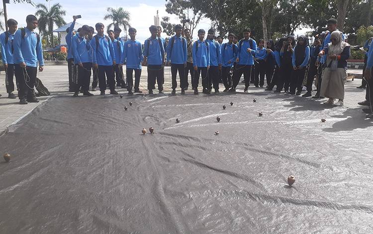 Anak-anak SMA 3 Negeri Pangkalan Bun saat pemanasan memainkan gasing sebelum kegiatan dimulai, Kamis, 7 Maret 2024. (FOTO: NURITA)