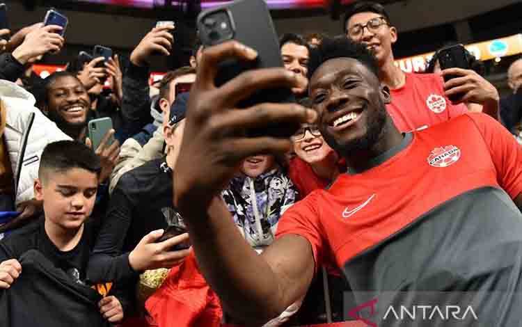 Arsip foto - Bintang tim nasional Kanada Alphonso Davies berswafoto dengan suporter setelah memberi tanda tangan usai pertandingan CONCACAF Nations League 2022-23 melawan Curacao di Stadion BC Place, Vancouver, Kanada, Kamis (9/6/2022). (ANTARA/AFP/Don MacKinnon)