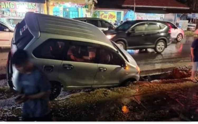 Mobil terperosok dalam lubang di Jalan Rajawali, Palangka Raya. (FOTO: IST)