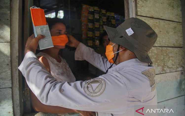 Petugas Badan Penanggulangan Bencana Daerah (BPBD) Provinsi Maluku Utara memasangkan masker kepada warga yang terdampak abu vulkanik Gunung Ibu di Desa Sangaji Nyeku, Kabupaten Halmahera Barat, Maluku Utara, Selasa (14/5/2024). ANTARA FOTO/Andri Saputra/nym.