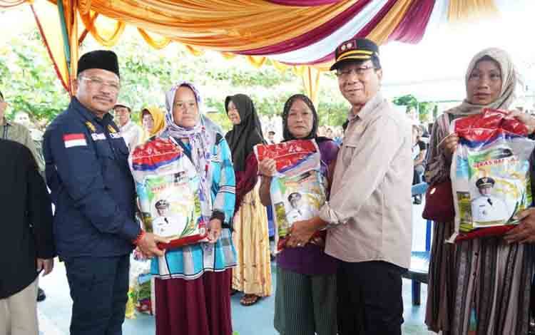 Sekda Provinsi Kalimantan Tengah, H. Nuryakin dan Sekda Bartim Panahan Moetar secara simbolis menyerahkan sembako kepada masyarakat di Kelurahan Ampah Kota, Kamis, 13 Juni 2024. (FOTO: IST)