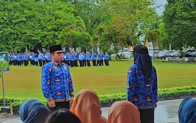 Staff Ahli Wali Kota Palangka Raya Alman Parluhutan Pakpahan saat menyampaikan laporan kepada Pj Wali Kota Palangka Raya Hera Nugrahayu sebelum apel dimulai (Foto : PATHUR)