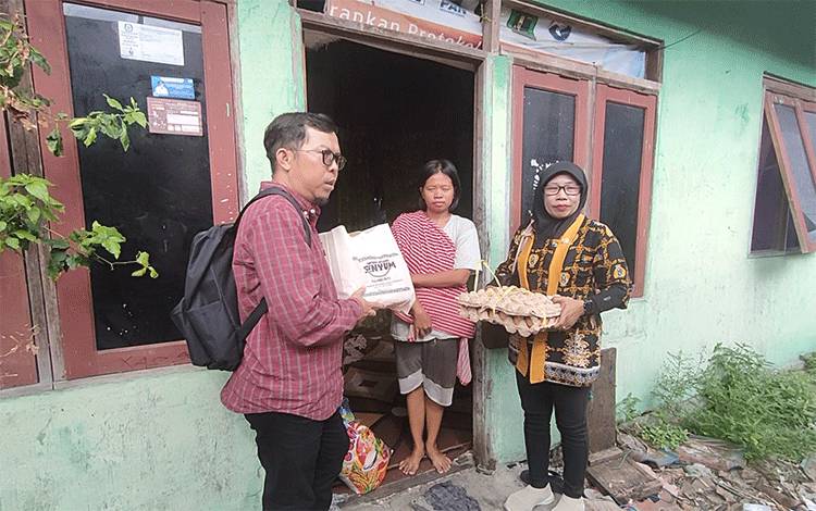 Ketua Kantong Berbagi Senyum Dodi (kemeja merah kanan) saat menyalurkan paket sembako kepada masyarakat di daerah Dermaga Kereng Bangkirai, Jumat, 19 Juli 2024 (Foto : PATHUR)