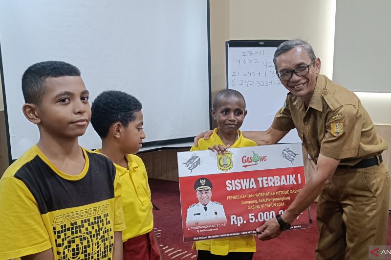 Asisten III Setda Kota Jayapura Nur Bi Adji saat menyerahkan penghargaan berupa uang tunai kepada salah satu peserta terbaik dalam kegiatan pembinaan minat bakat dan kreativitas siswa Numbay Pintar dengan metode gasing di Jayapura, Selasa (13/8) (ANTARA/Ardiles Leloltery)